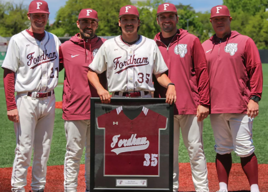 Kai Reum with Fordham baseball staff holding framed jersey